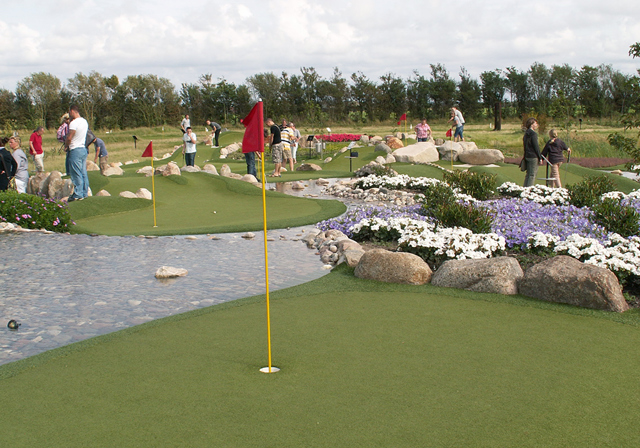 Adventure golf green next to water and flowers